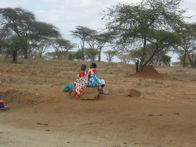 Two Masaai women sitting beside the road waiting for a ride somewhere